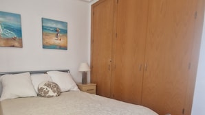 Ein Schlafzimmer mit einem Bett, einem Nachttisch, einem Holzschrank und zwei Wandbildern.