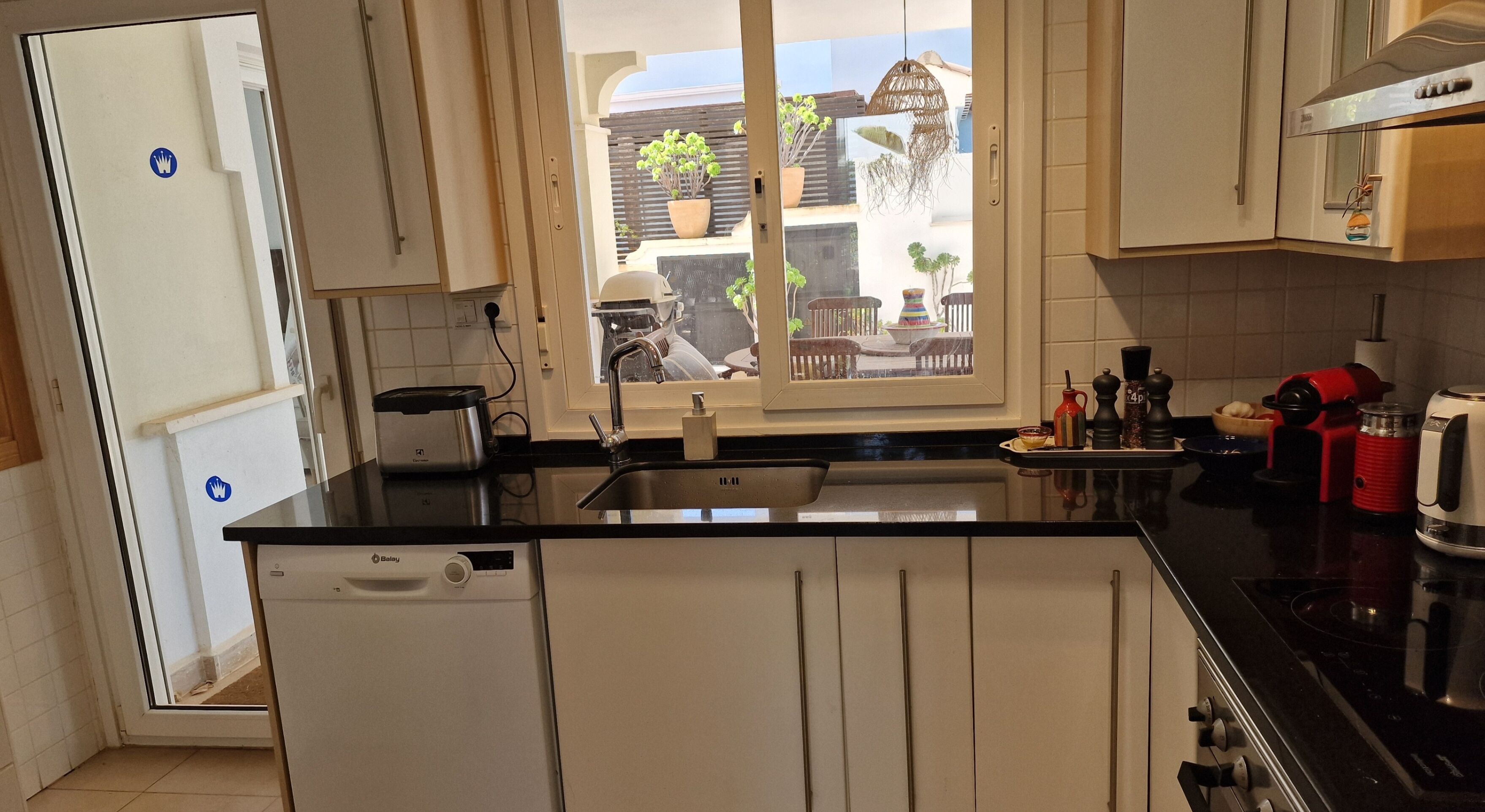 A compact kitchen with a dishwasher, a toaster, a sink, and a stove.