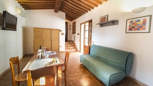 Un coin repas avec une table en bois dressée pour deux personnes, un canapé et un escalier menant à un niveau supérieur.
