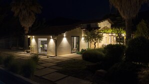 Una casa con un camino de piedra que lleva a la entrada, rodeada de palmeras y arbustos cuidados.