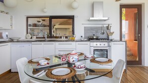 A modern kitchen with white cabinetry, a glass dining table with placemats, and a visible stove.