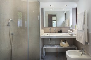 Ein modernes Badezimmer mit Duschabtrennung aus Glas, einem Waschbecken mit Spiegel darüber und einem Bidet.