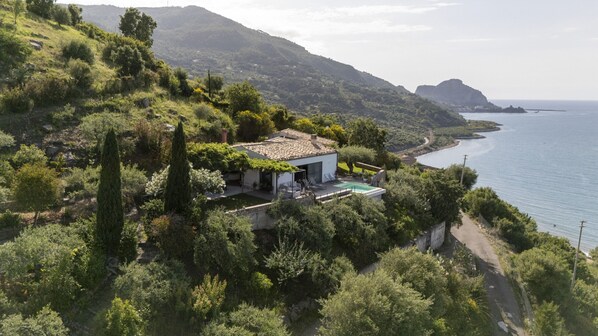Una casa frente al mar con piscina privada, rodeada de exuberante vegetación.