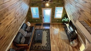 A high-ceilinged wooden interior with a central skylight, a sofa, a coffee table, and a piano. - The Lookout | Secluded A-Frame | Hot Tub | Games (Campton)