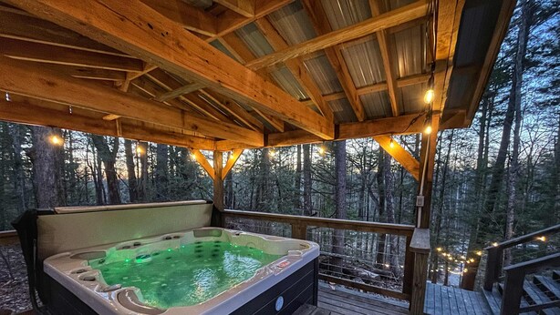 A hot tub on a wooden deck with a forest backdrop. - The Lookout | Secluded A-Frame | Hot Tub | Games (Campton)