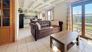A spacious living area with a leather sofa, a wooden coffee table, and a kitchen in the background. - Lovely apartment in villa for 6 people with WIFI and TV (Bruges)