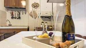 Een aanrecht met een fles champagne, een schaal fruit en een decoratief object.