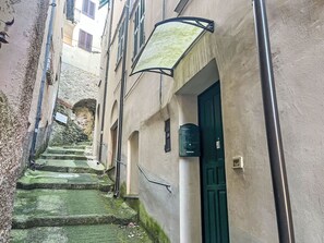 Une ruelle étroite avec des marches en pierre menant à un immeuble doté d’une porte verte et d’une boîte aux lettres.