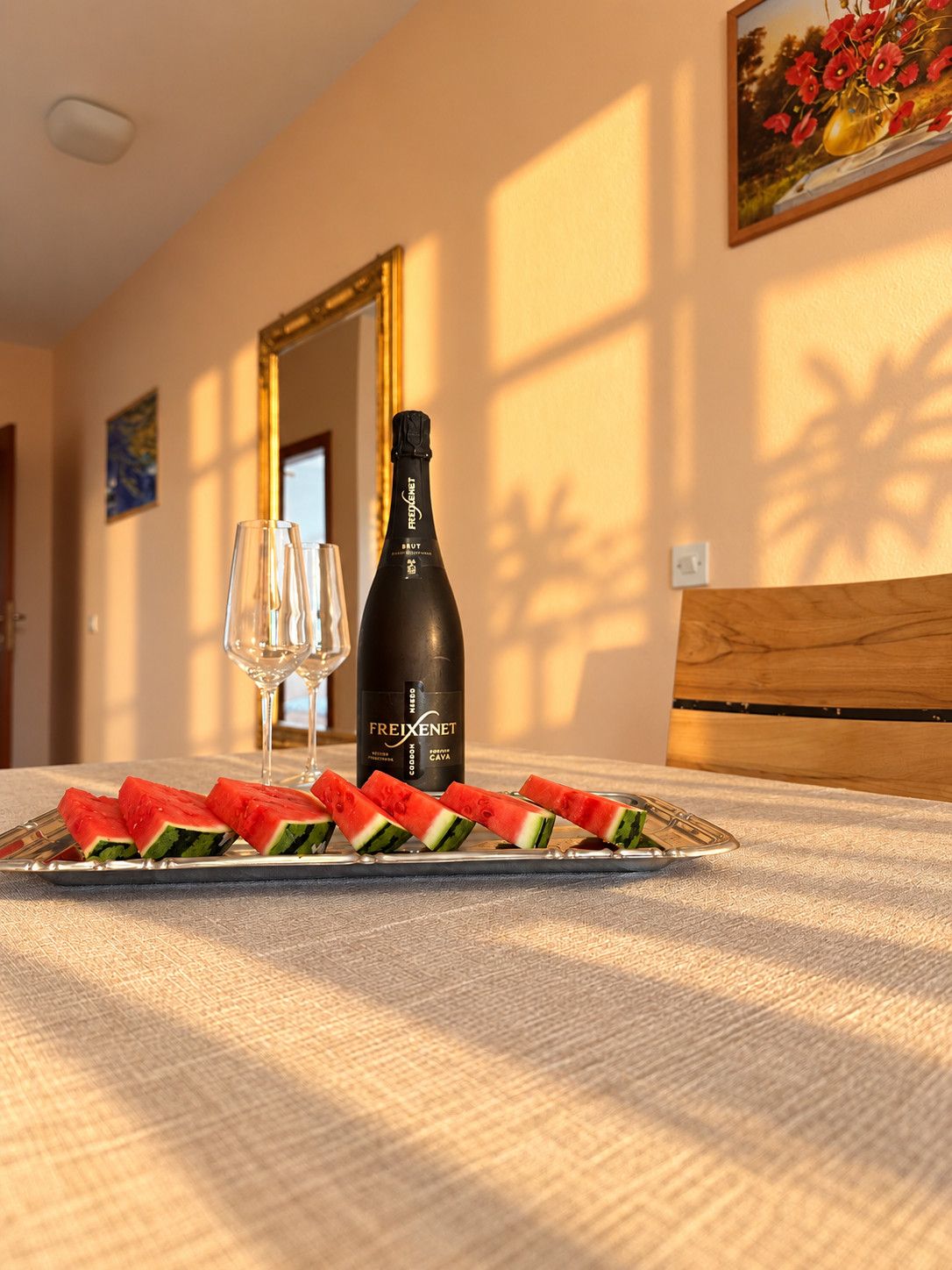 A table with a bottle of Freixenet wine, a glass, and watermelon slices.