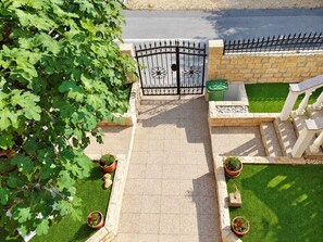 A gated entrance with a paved pathway leading to a well-maintained lawn area. - Apartment Bodulo 2 (Povljana)