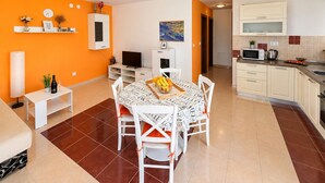 Un espacio habitable compacto con comedor, kitchenette y televisor.