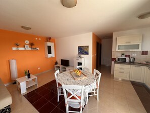 Un espacio habitable compacto con comedor, cocina y una pequeña televisión.