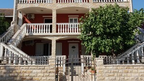 Un immeuble à plusieurs étages, doté d’une façade rouge, de balcons blancs et d’une entrée en pierre.