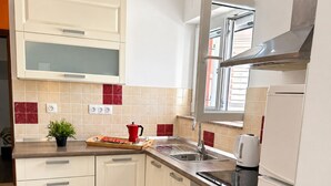 Una cocina moderna con muebles blancos, un lavamanos de acero inoxidable y un horno empotrado.
