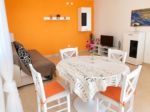 A dining area with a round table, white chairs, and a tablecloth with printed text.
