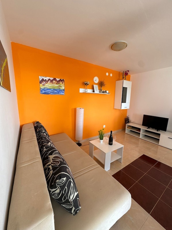 Una sala de estar moderna con un sofá beige, una mesa de centro blanca y un mueble para televisor.
