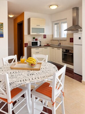 A modern kitchen with white cabinets, a microwave, a stove, and a refrigerator.
