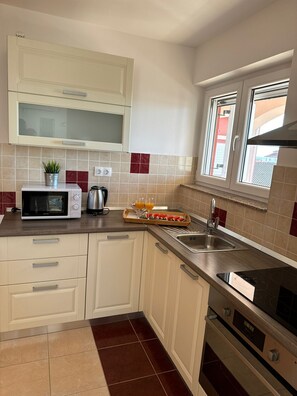 Een koelkast, een oven, een waterkoker, kookgerei, borden en bestek