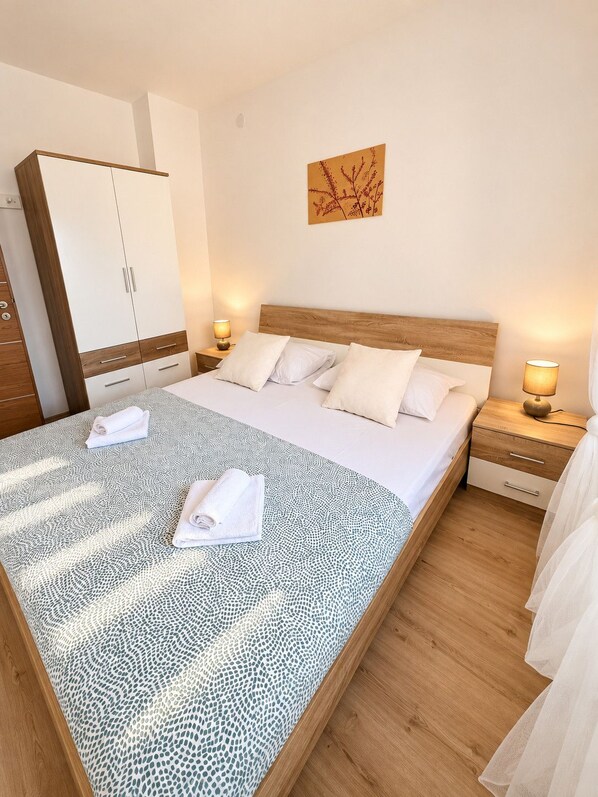 Habitación de hotel con una cama grande, dos mesitas de noche, un armario y una obra de arte colgada en la pared.