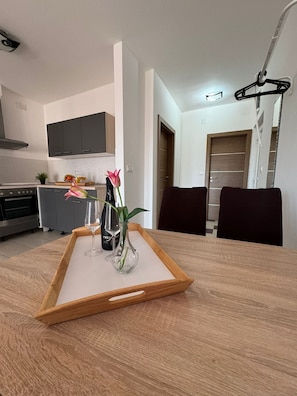 A modern kitchen with grey cabinets, a wooden countertop, and a dining area with a wooden table and chairs. - Beautiful Apartment Bodulo 6 (Povljana)