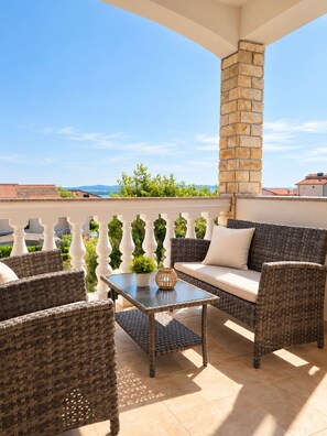 A balcony with wicker furniture, a stone pillar, and a view of the landscape.
