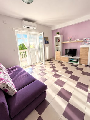A living room with a purple sofa, a television, and a checkered floor.
