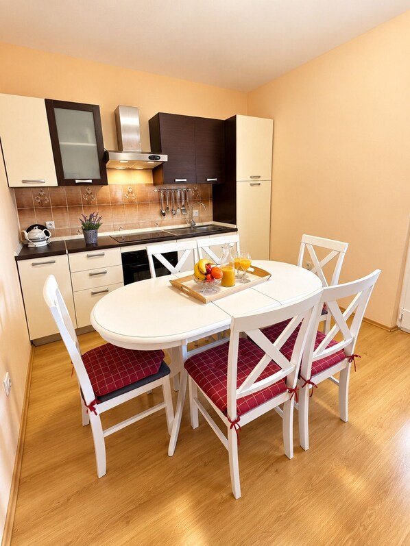 A compact kitchen with a dining area, white cabinetry, and a small countertop.