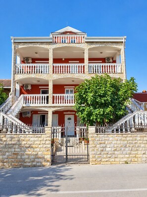 A multi-story building with a central entrance, balconies, and a stone facade.
