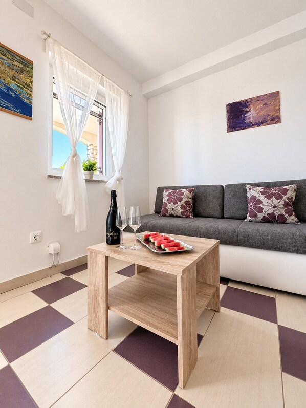 A modern living room with a sofa, a coffee table with a watermelon tray, and a bottle of wine.