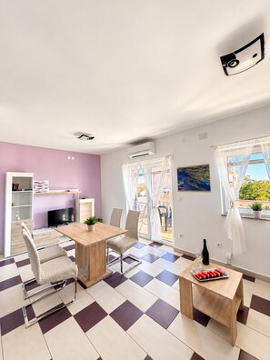 A modern living room with a checkered floor, a wooden dining table, and a TV.
