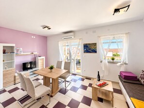 A modern living room with a dining area, a TV, and a sofa.