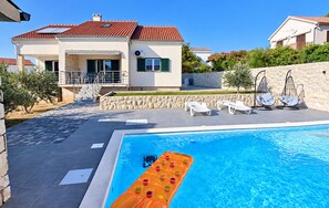 A residential property with a swimming pool, outdoor seating, and a stone wall.