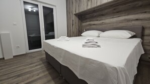 A bedroom with a bed, a wooden headboard, a sliding door, and a small bedside table. - Villa Pauliana (Povljana)