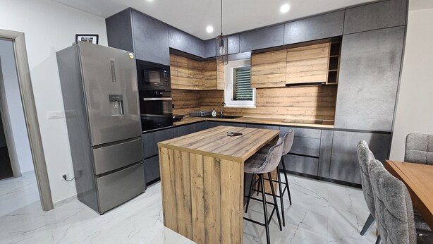 A modern kitchen with a central island, stainless steel appliances, and wooden cabinetry. - Villa Pauliana (Povljana)
