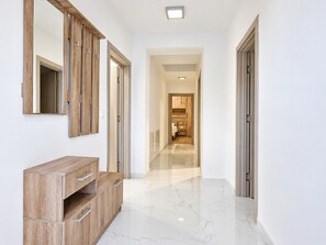 A hallway with a wooden vanity, a mirror, and a door leading to a bedroom.