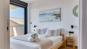A modern bedroom with a large bed, a painting of a lighthouse, and a wooden nightstand with a basket. - Villa Maiorum with indoor heated pool (Povljana)