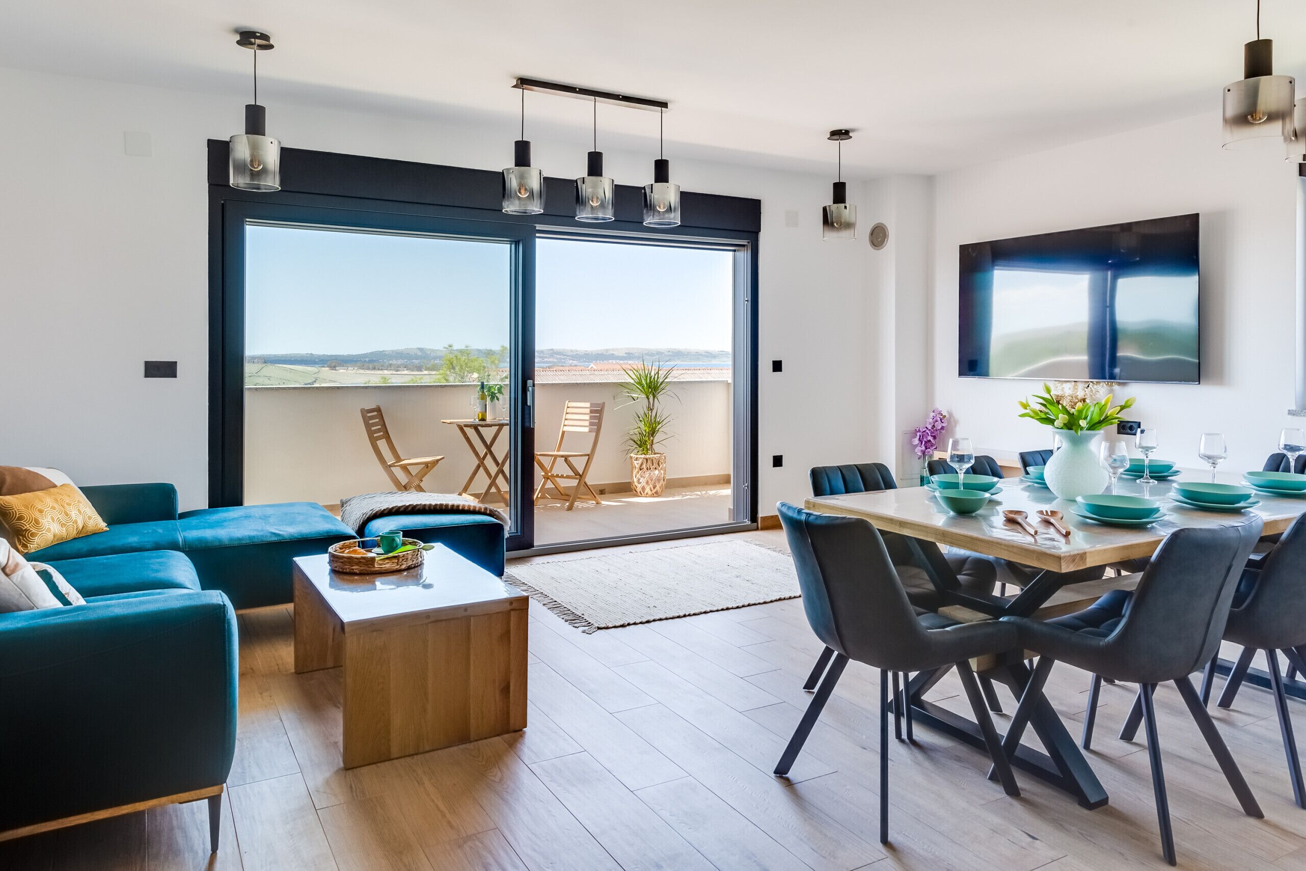 A modern living room with a sofa, coffee table, and dining area with chairs and a table set for a meal.