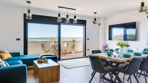 A modern living room with a sofa, coffee table, and dining area with chairs and a table set for a meal. - Villa Maiorum with indoor heated pool (Povljana)