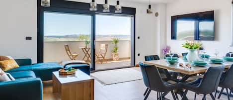 A modern living room with a sofa, coffee table, and dining area with chairs and a table set for a meal.