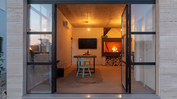 An open-plan living space with a fireplace, a dining area, and a TV mounted on the wall. - Beautiful Villa Aria (Zadar)