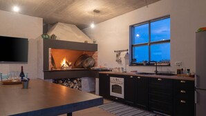 A modern kitchen with a built-in stove, a large window, and a flat-screen TV mounted on the wall. - Beautiful Villa Aria (Zadar)