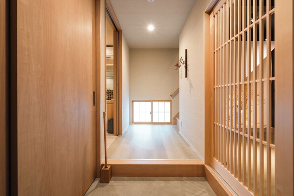 Un pasillo con suelo de madera, una puerta corrediza y vistas a una habitación con un amplio ventanal.
