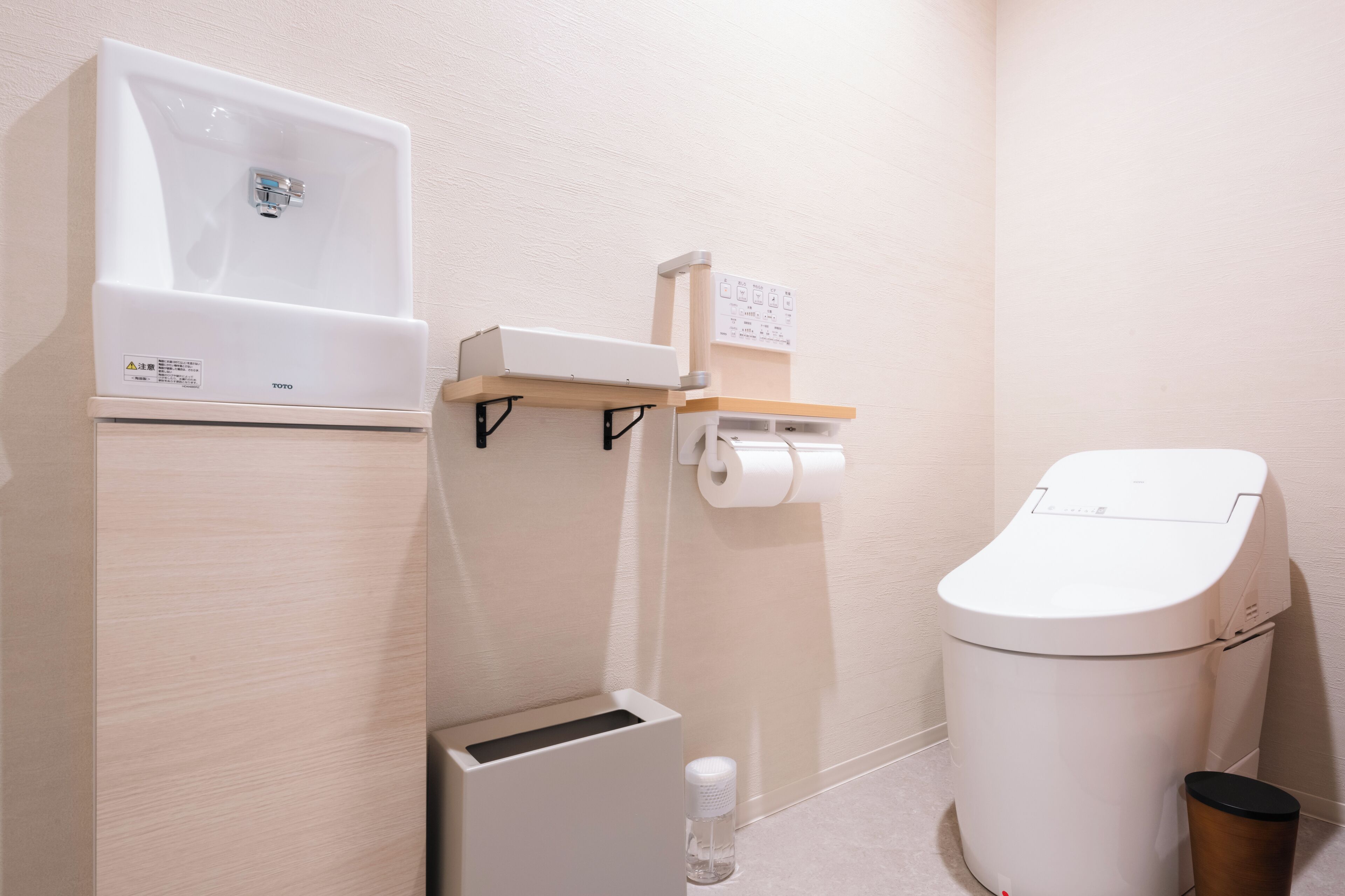 Un baño moderno con inodoro, lavamanos y un cubo de basura.