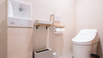 Un baño moderno con inodoro, lavamanos y un cubo de basura.