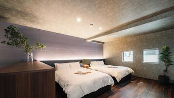 A modern bedroom with two beds, a wooden dresser, a potted plant, and a large window with blinds.