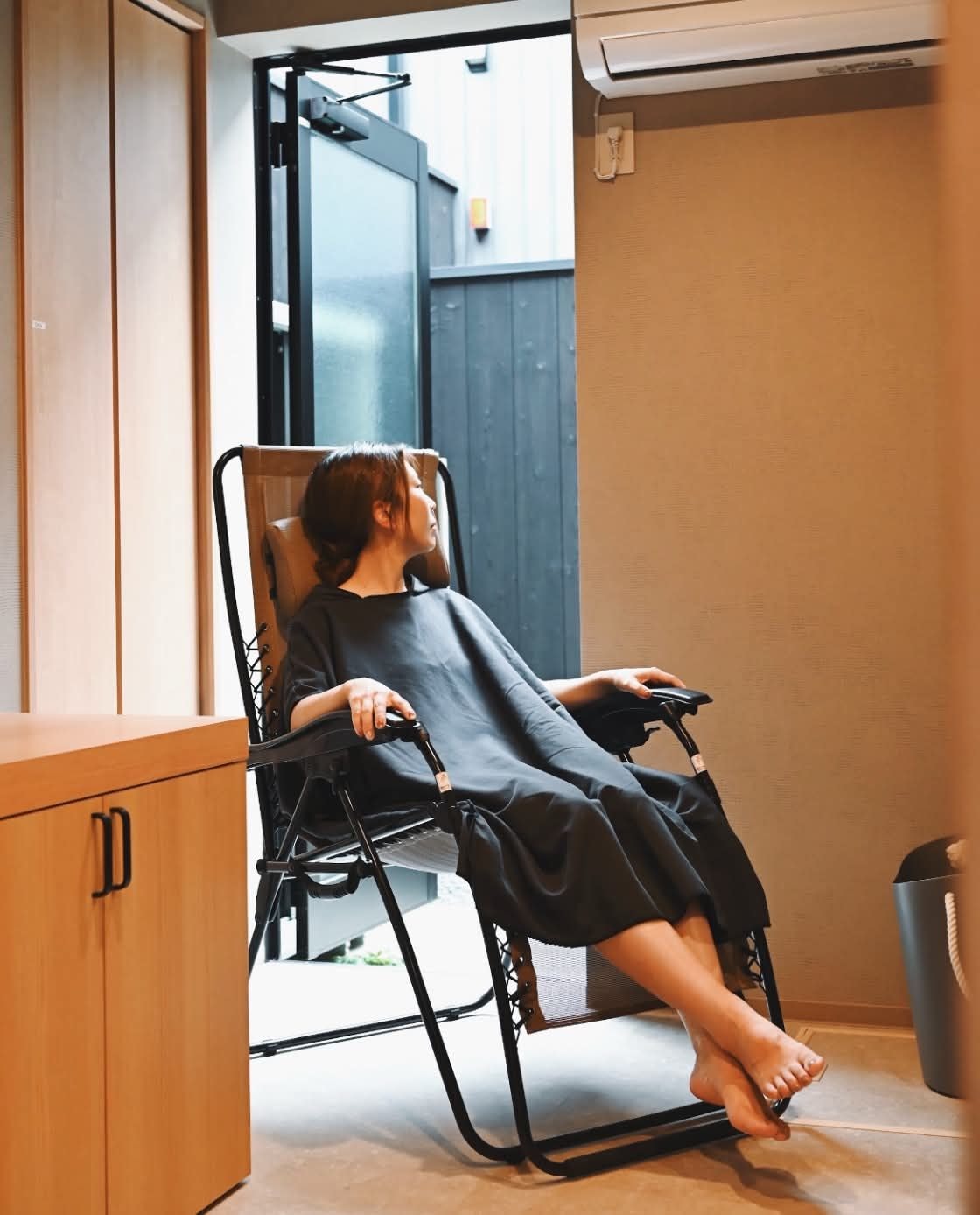 A person seated in a chair with a view of the outdoors.