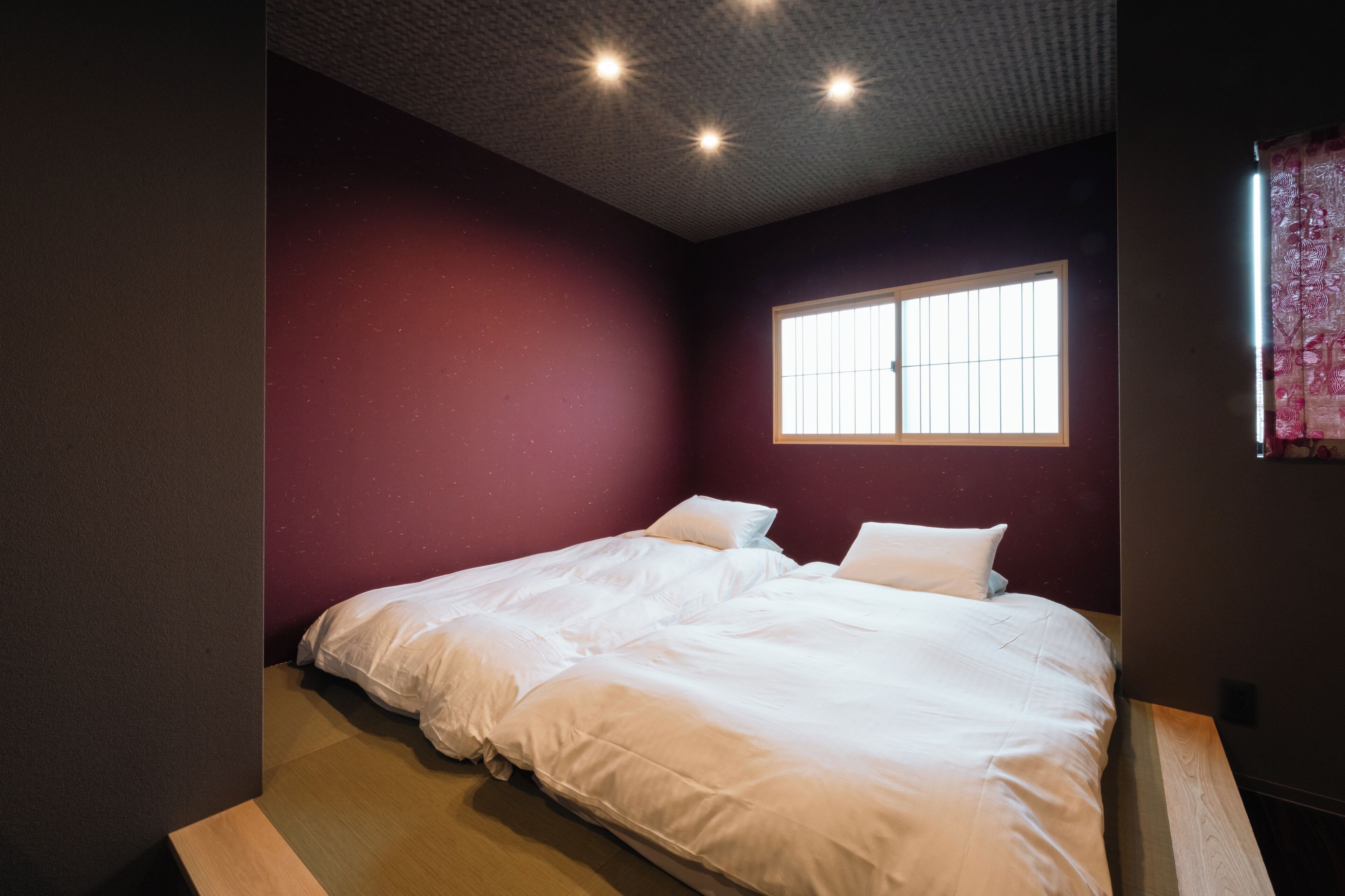 Un dormitorio con dos camas, una ventana e iluminación empotrada en el techo.