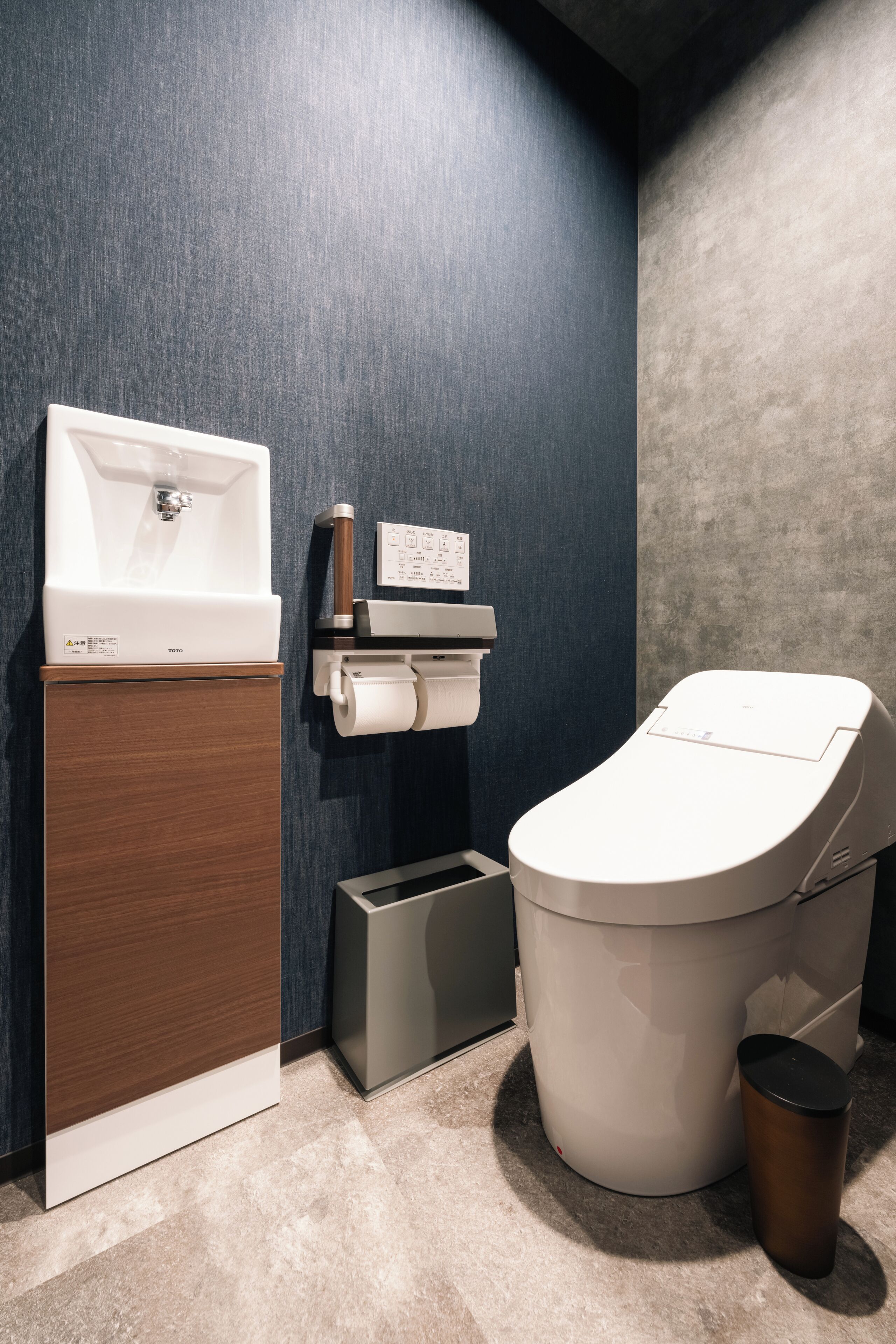 A modern bathroom with a sink, toilet, and trash bin.