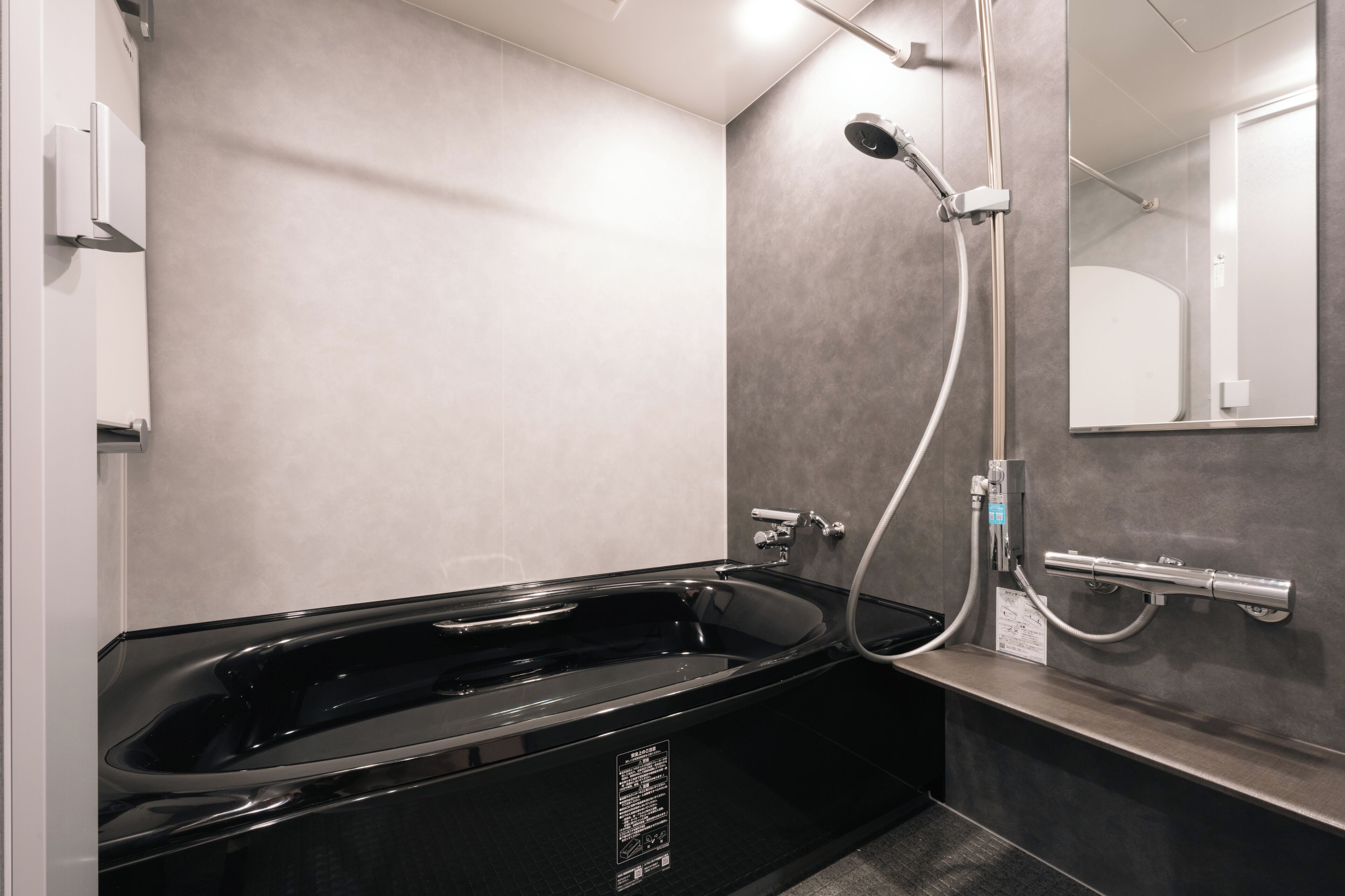 A modern bathroom with a black jacuzzi tub, a handheld showerhead, and a wall-mounted mirror.