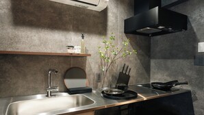 Una cocina moderna con un lavamanos de acero inoxidable, una hornilla negra y un estante de madera sobre el lavamanos.